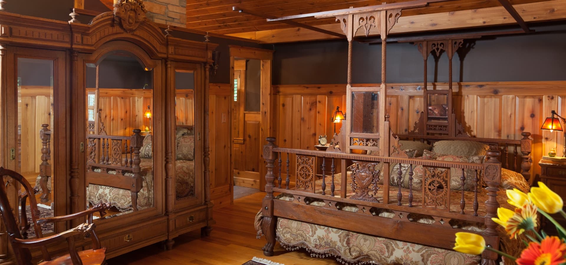 A cozy wooden bedroom featuring ornate furniture and warm lighting.