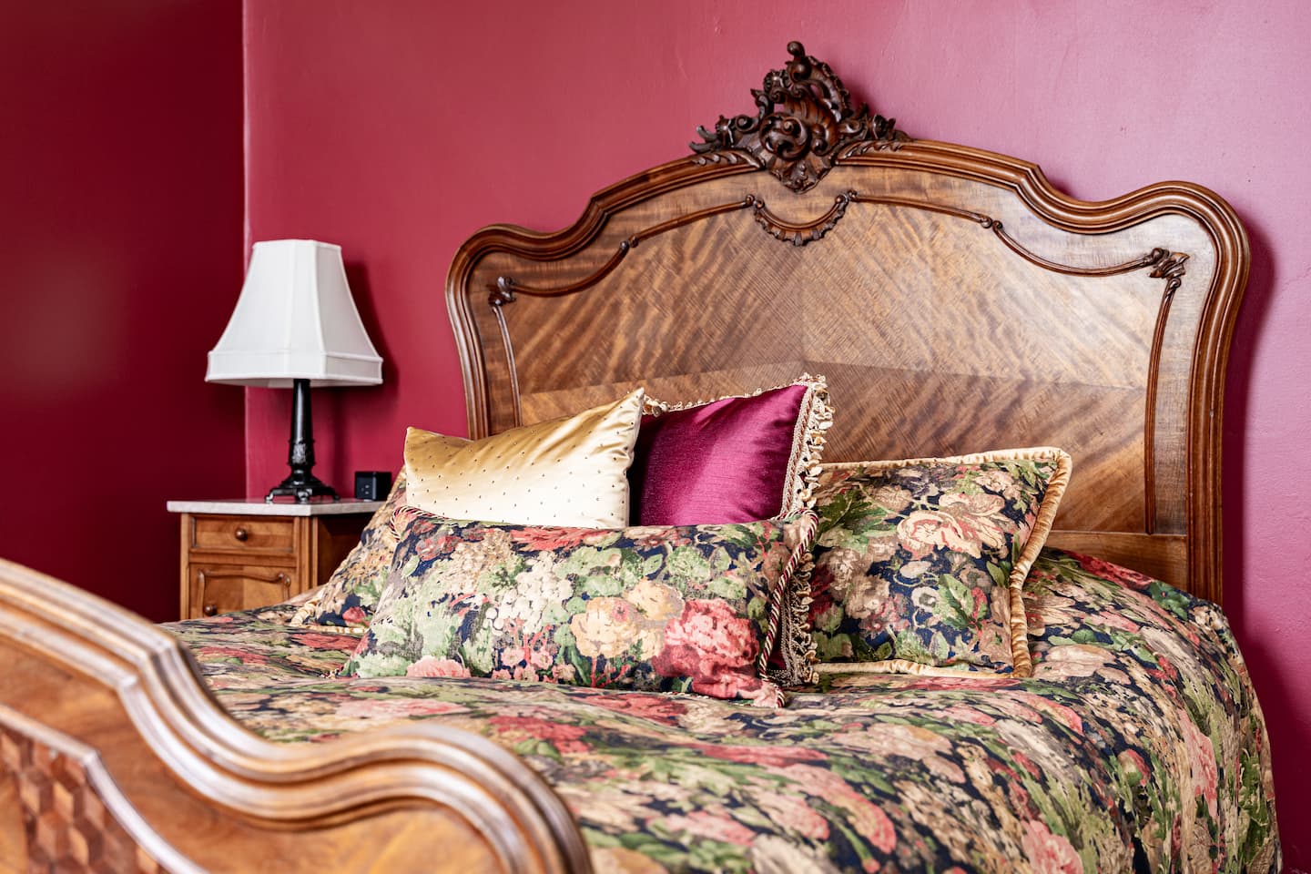 Closer image of queen size bed; ornamental antique frame has carved roses on foot and headboard