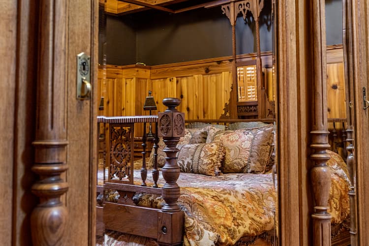 Reflection of the king sized bed in the antique armoire