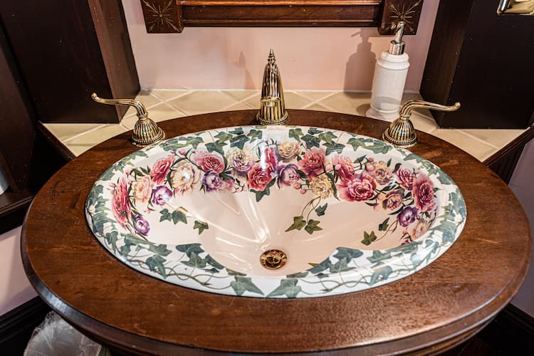 Antique flowered sink surrounded by dark wood