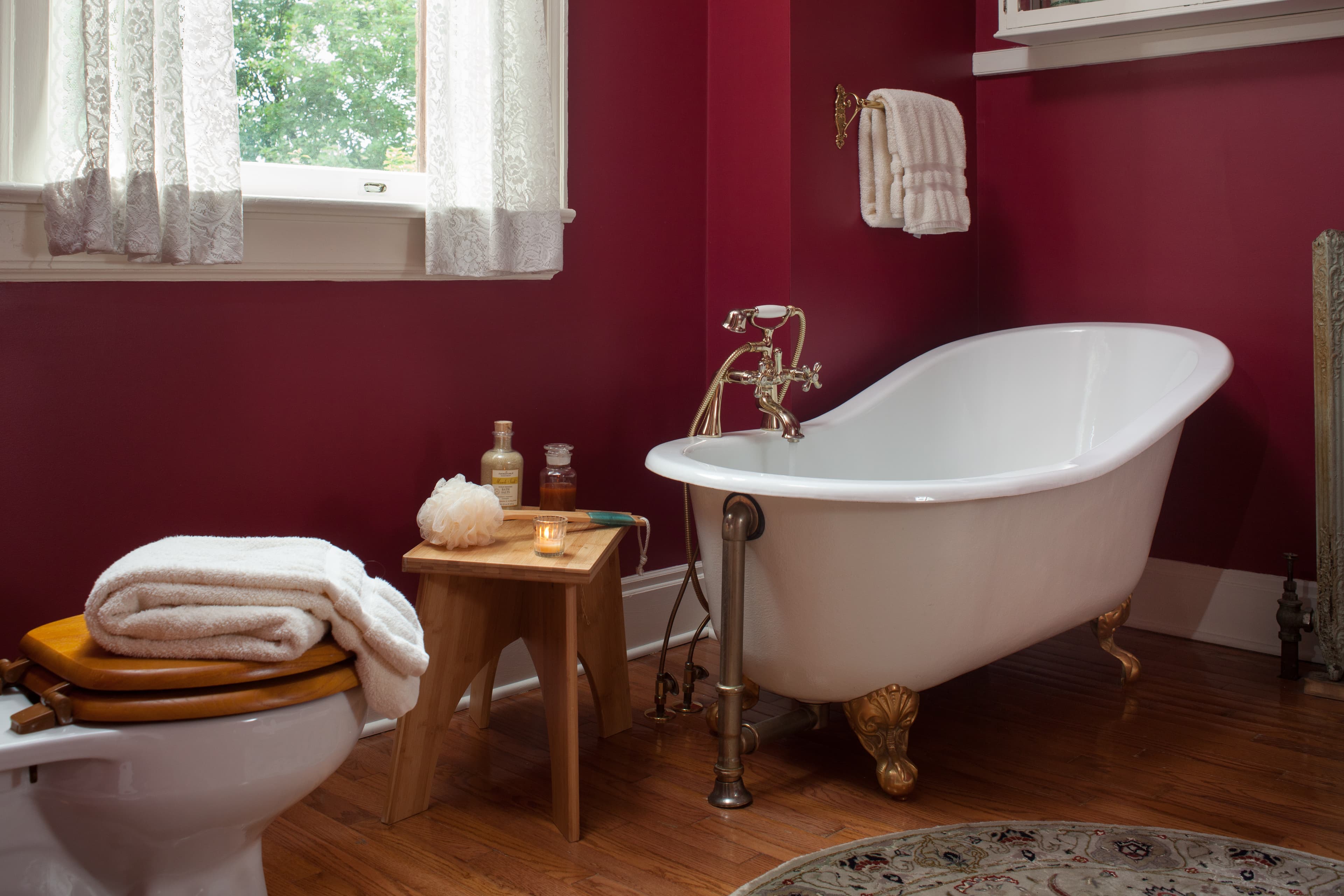 Carl's bathroom; claw-foot slipper tub with shower wand attachment; bath package next to tub on teak bench.