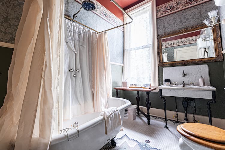 Private bathroom across the hall with the shower/tub combo, toilet and antique sink