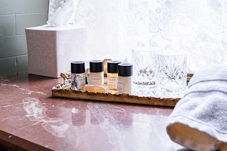 Tray of overnight amenities including shampoo, lotion, conditioner, glasses and more