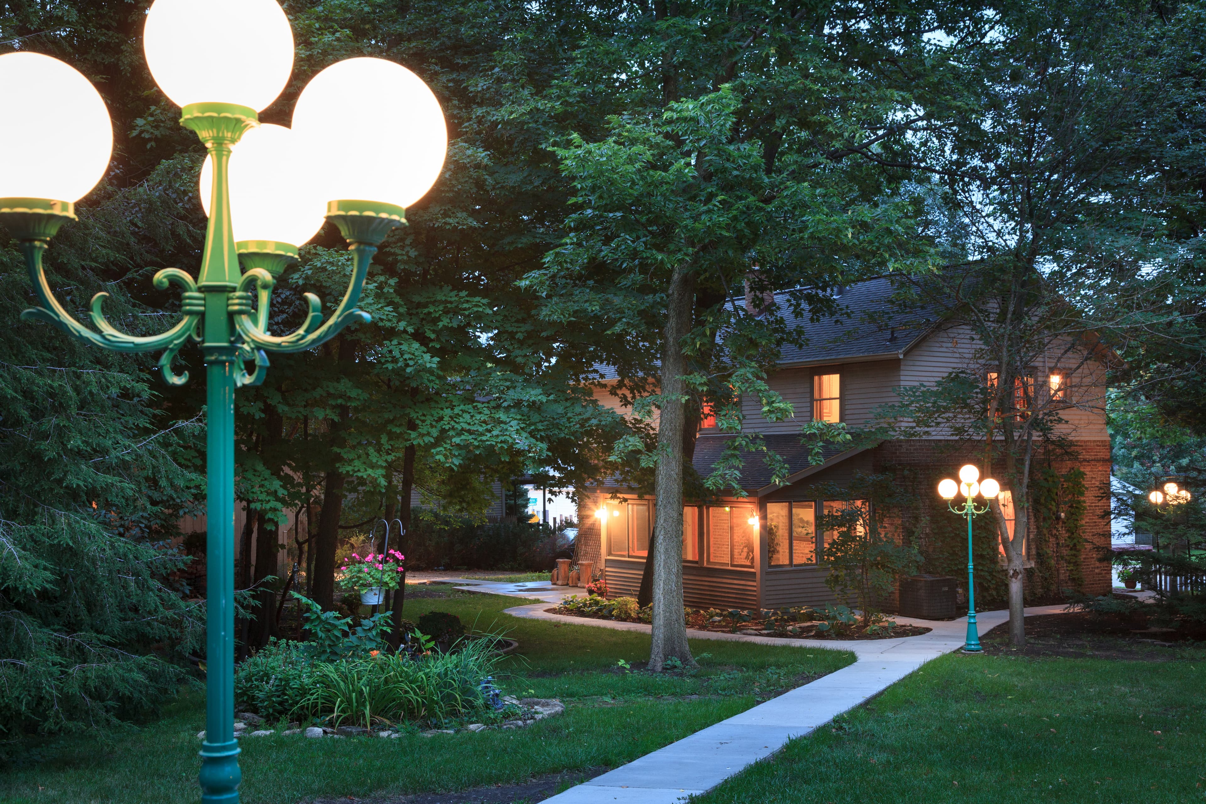 Sunset view of Carriage House from Main House. Lighted sidewalk between buildings.