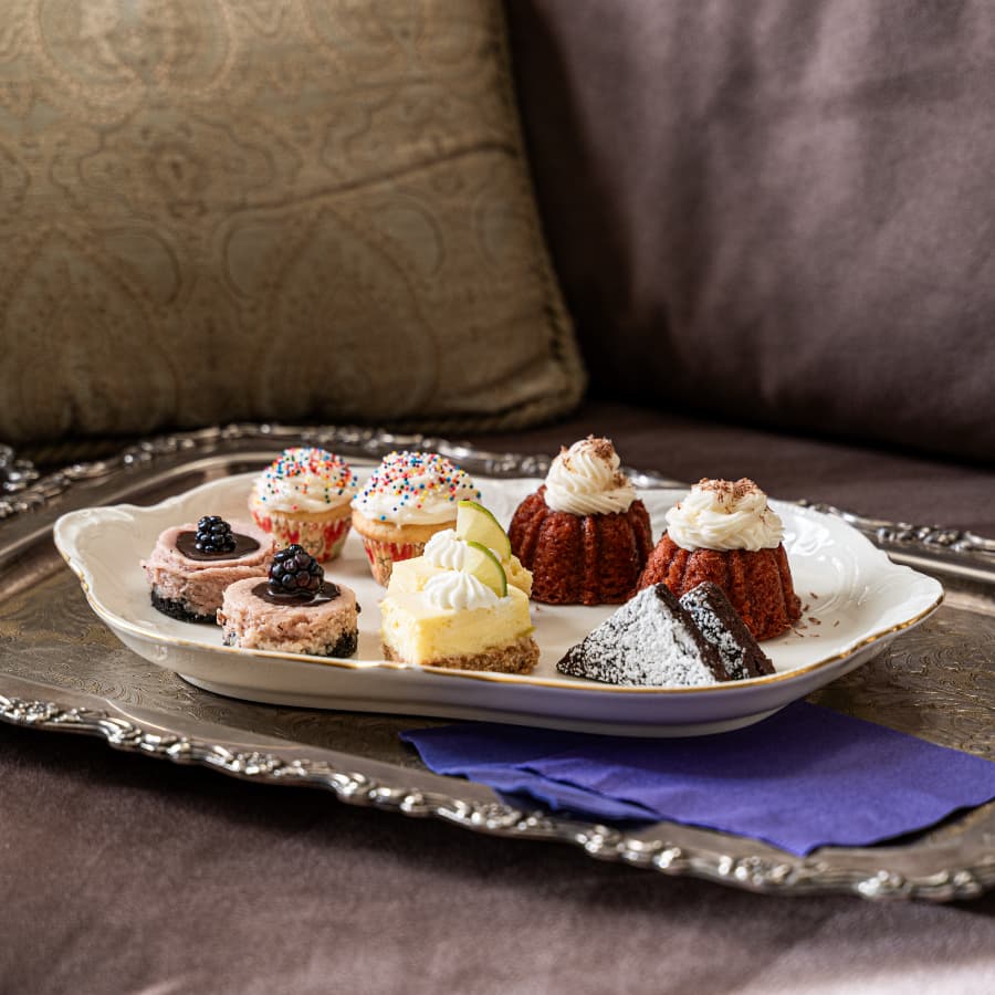A decorative platter holds an array of colorful mini cakes and desserts.