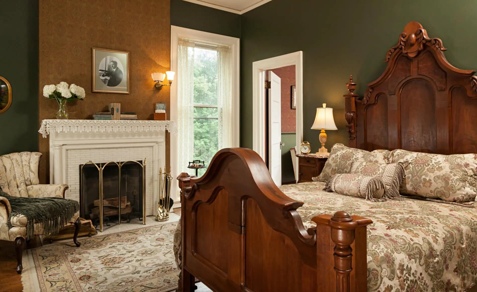 A cozy bedroom featuring a wooden bed, patterned bedding, an ornate fireplace, and vintage decor.