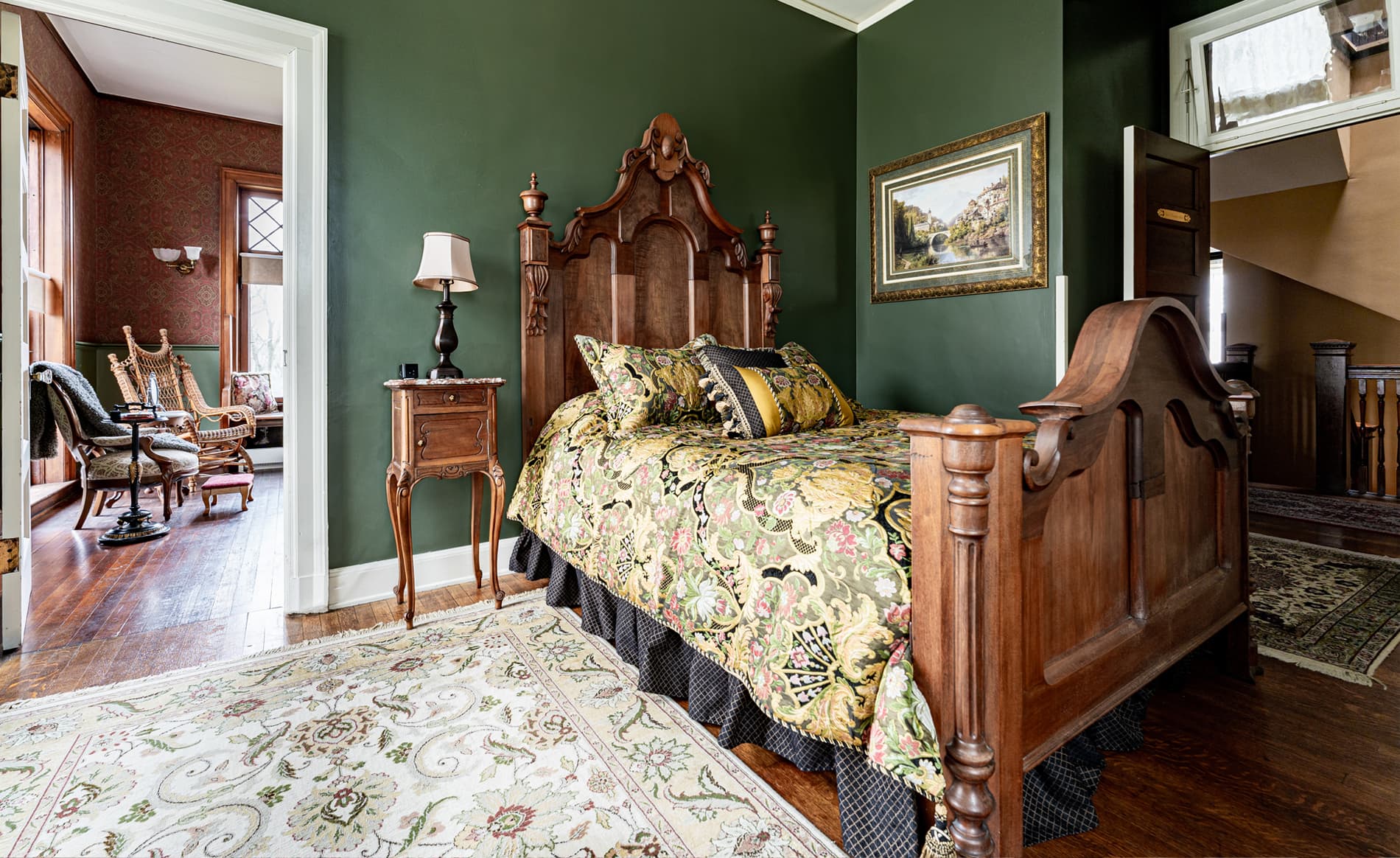 View of Carl's Suite from bedroom door; sculpted wood foot and head board on queen size bed, east window facing Carriage House