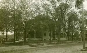 A historic building surrounded by trees, viewed from the street.