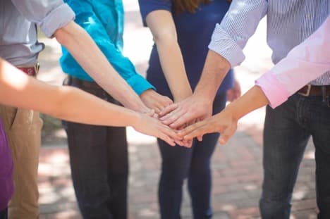 A group of hands stacked together in a circle. A group of hands stacked together in a circle.