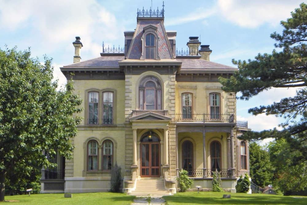Victorian-style mansion with a decorative facade and lush greenery.