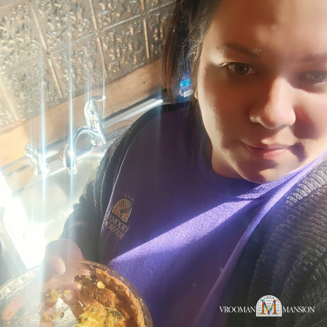 A person holds a pie dish in front of a sink, illuminated by sunlight.