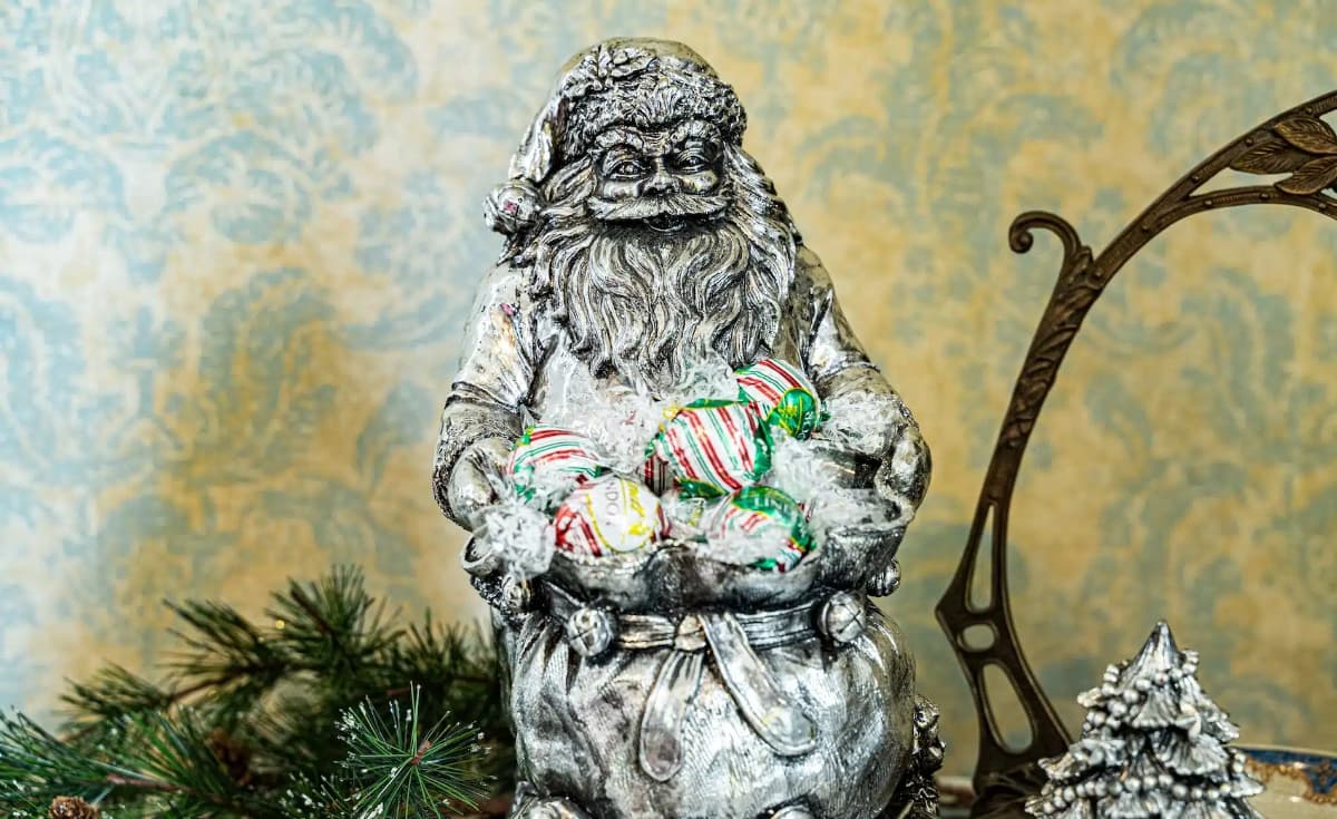 A decorative Santa figure holding colorful wrapped candies. A decorative Santa figure holding colorful wrapped candies.
