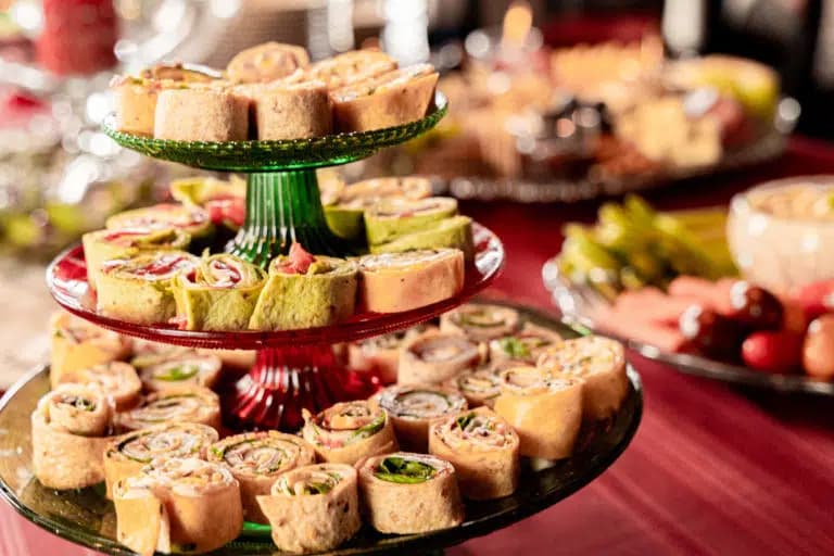 A tiered display of colorful rolled appetizers on a festive table.