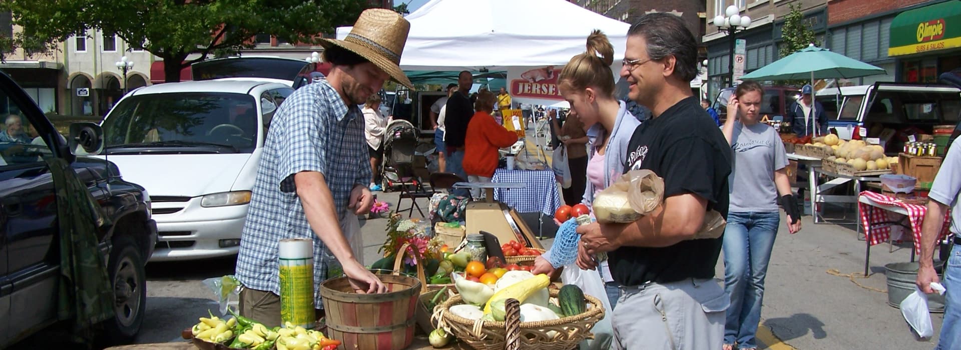 A bustling farmers' market scene with vendors selling fresh produce and customers browsing.