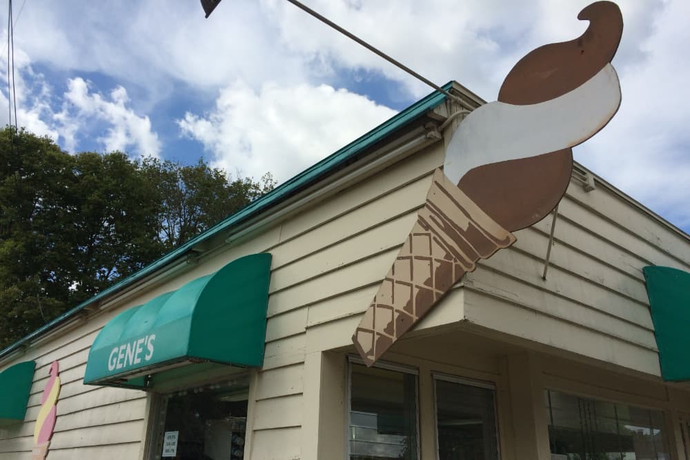 A vintage ice cream shop sign featuring a soft serve cone and the name "Gene's" displayed on a building.