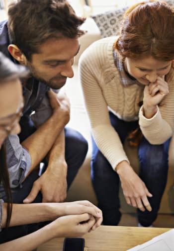 A group of three people gathered around a table, focused on a screen.