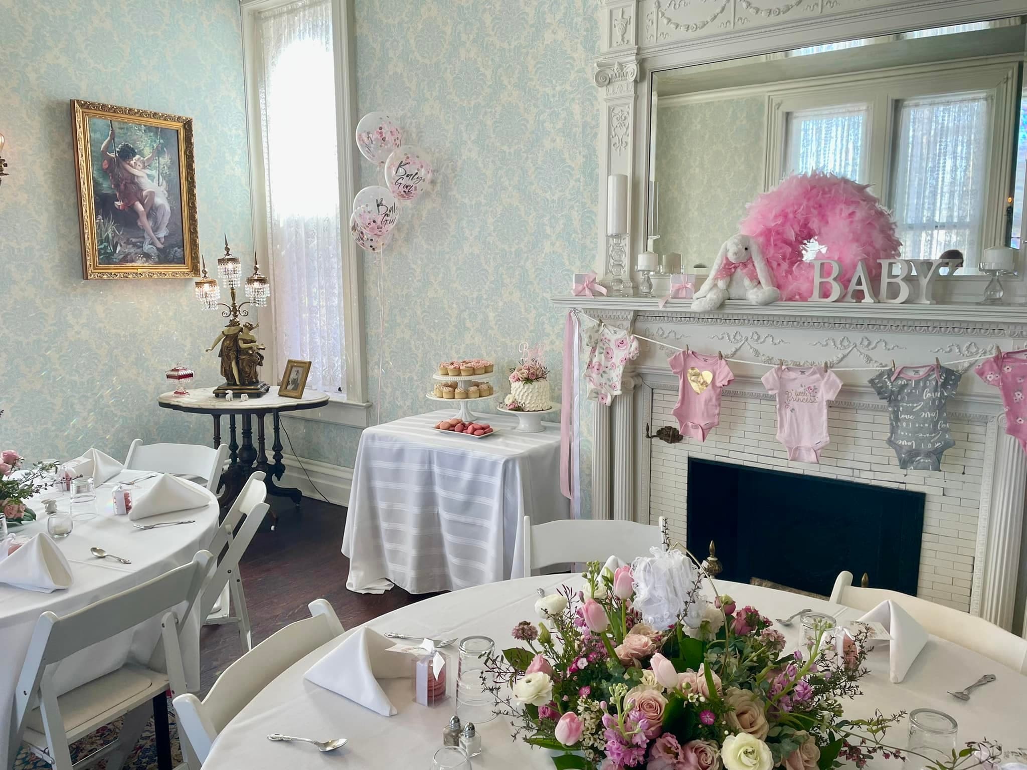 A beautifully decorated room for a baby shower featuring floral centerpieces, treats, and pink-themed decor.