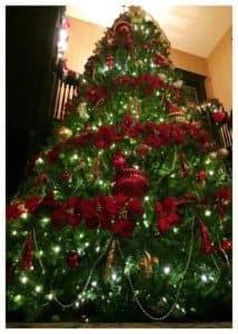 A beautifully decorated Christmas tree adorned with red flowers, gold ornaments, and twinkling lights.