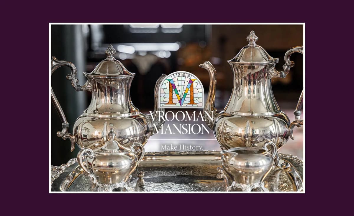 Silver tea service set displayed on a tray with the Vrooman Mansion logo.