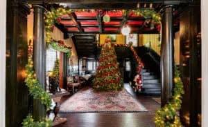 A warmly decorated entryway featuring a large Christmas tree and festive greenery.