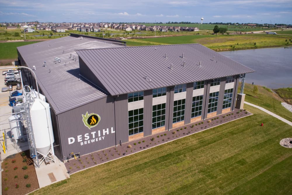 Aerial view of Destihl Brewery with a landscaped lawn and nearby residential area.