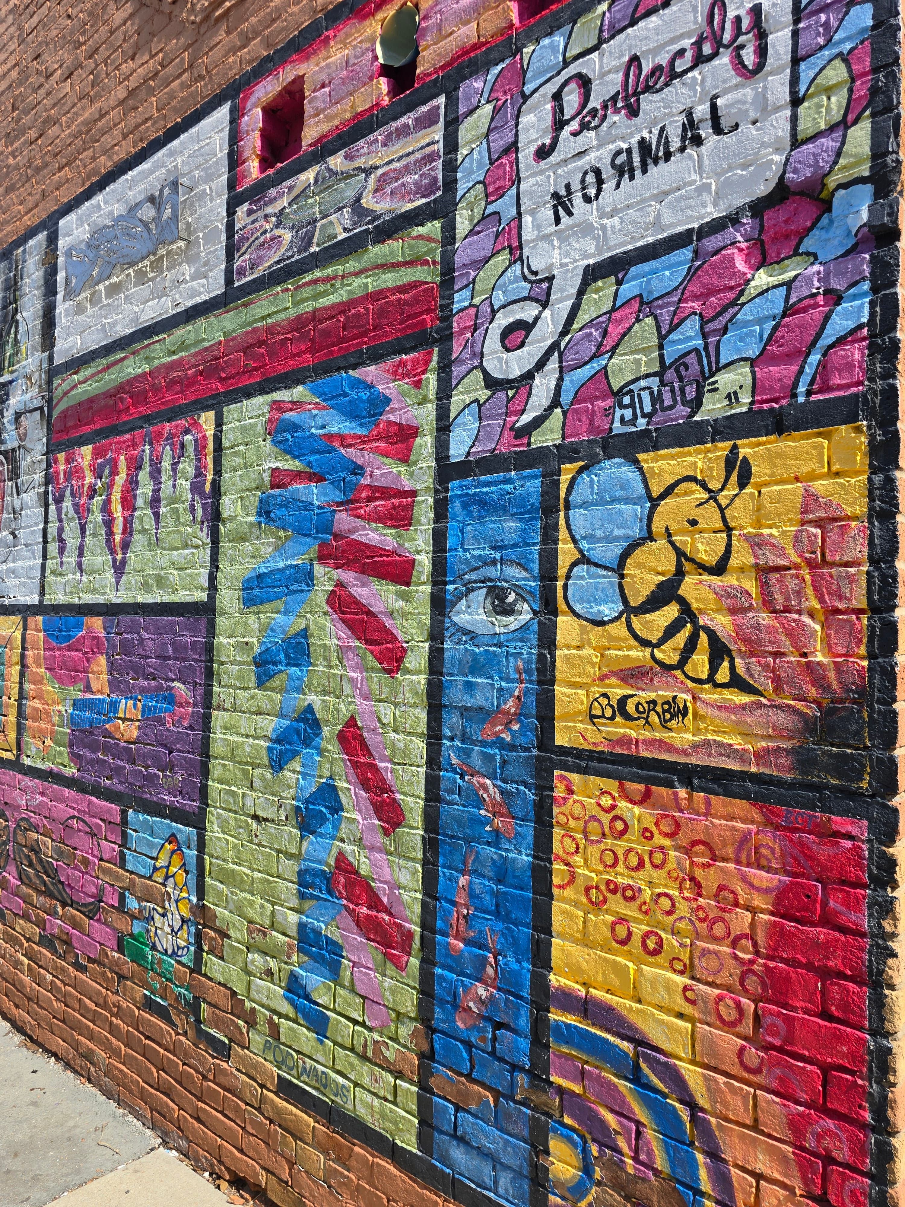 A vibrant mural featuring colorful designs, patterns, and the phrase "Perfectly Normal."