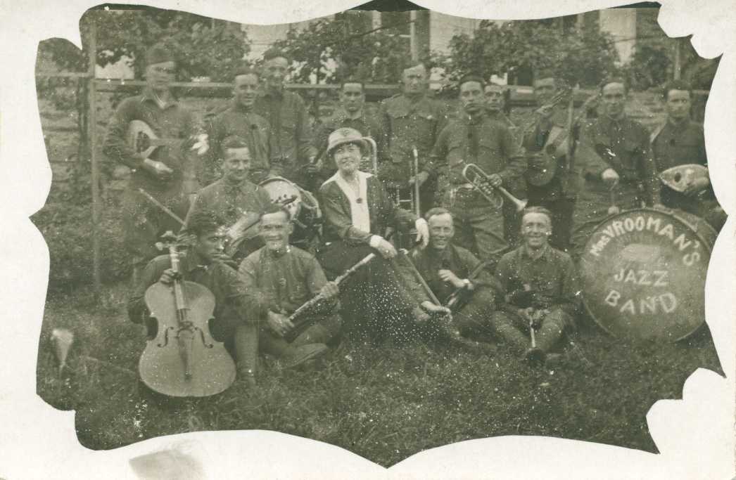 A historical black and white photo of a jazz band, featuring musicians and a woman seated in front of a large drum labeled "Mavrooman's Jazz Band."
