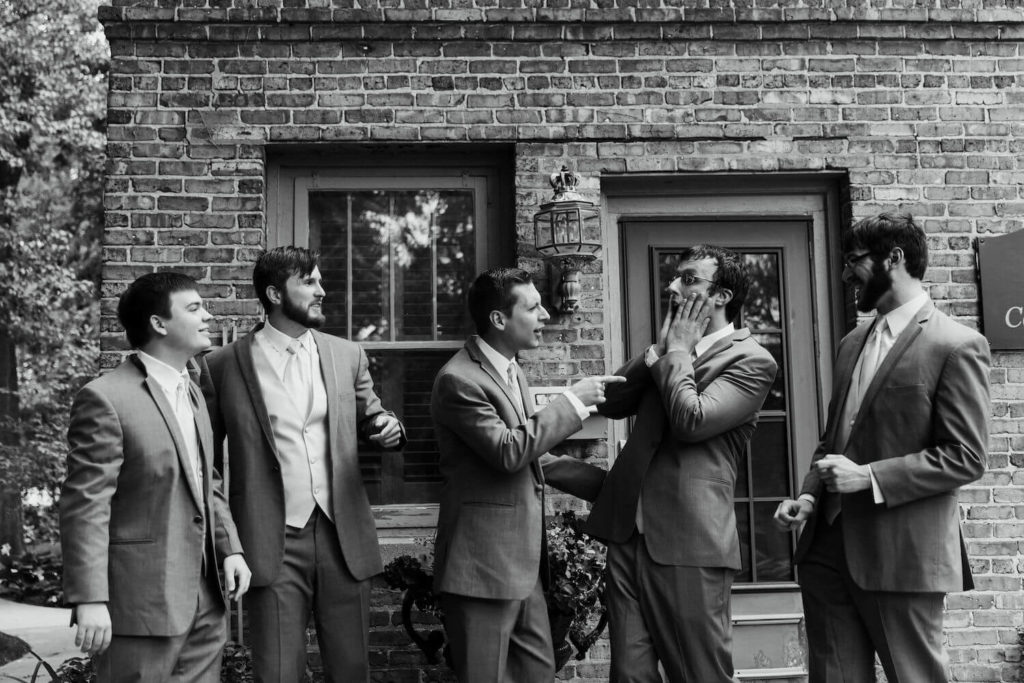 groomsmen outside the carriage house in black and white making funny faces at each other