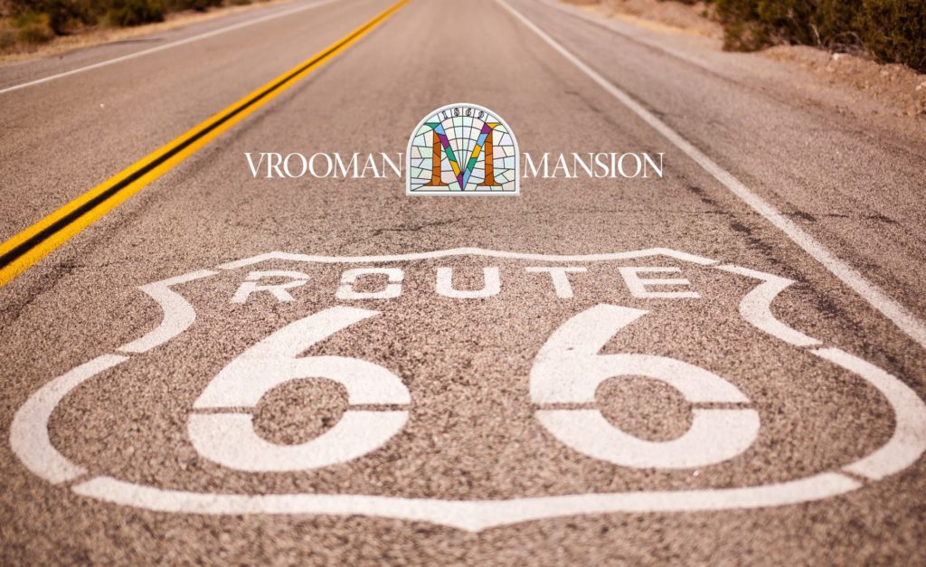 close up shot of a road with the route 66 symbol and Vrooman Mansion Logo