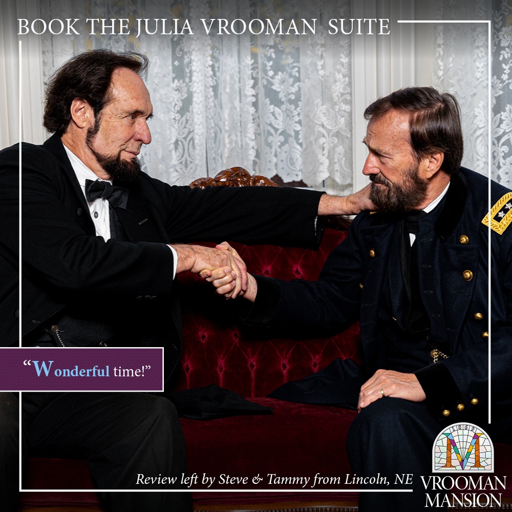 two actors portraying presidents Abraham Lincoln and Grant shake hands while sitting on a red velvet antique couch