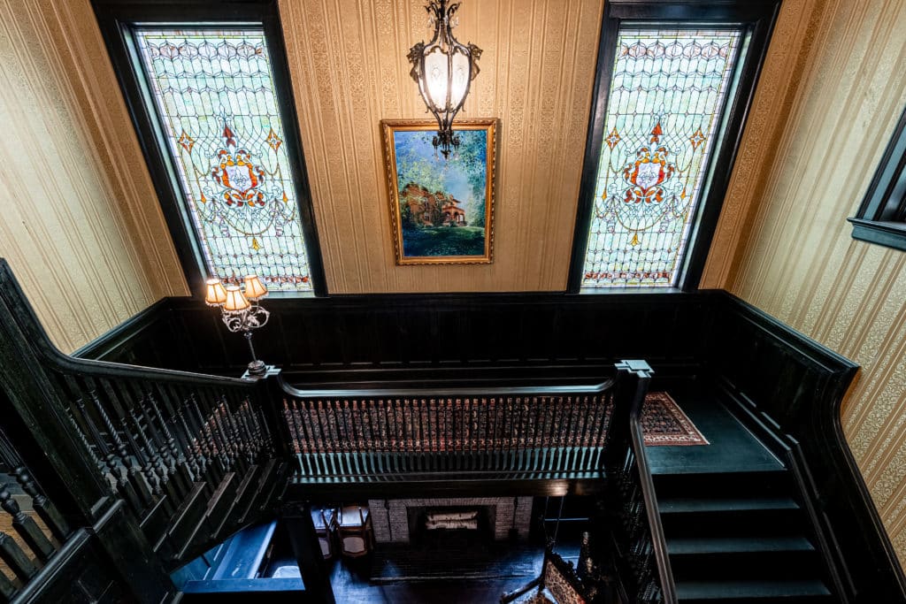 stained glass windows at the top of the foyer stairs