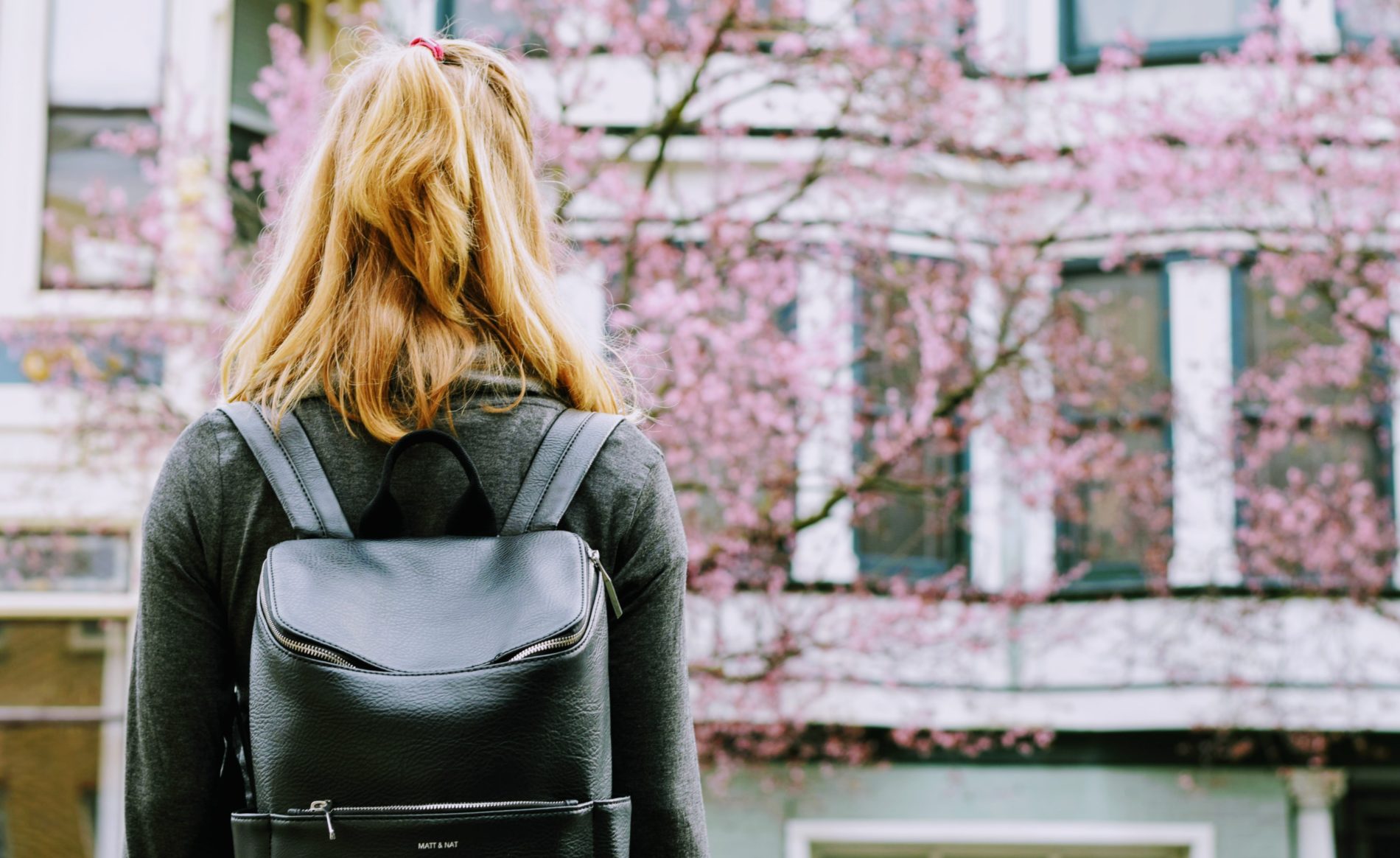 College student wearing a backpack facing a college building